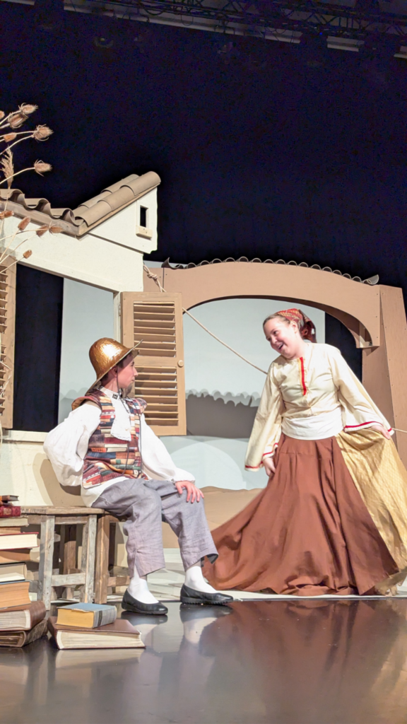 Don Quijote sitzt auf der Bank vor seinem Haus, Jacinta, die Wirtin kommt von rechts herbei